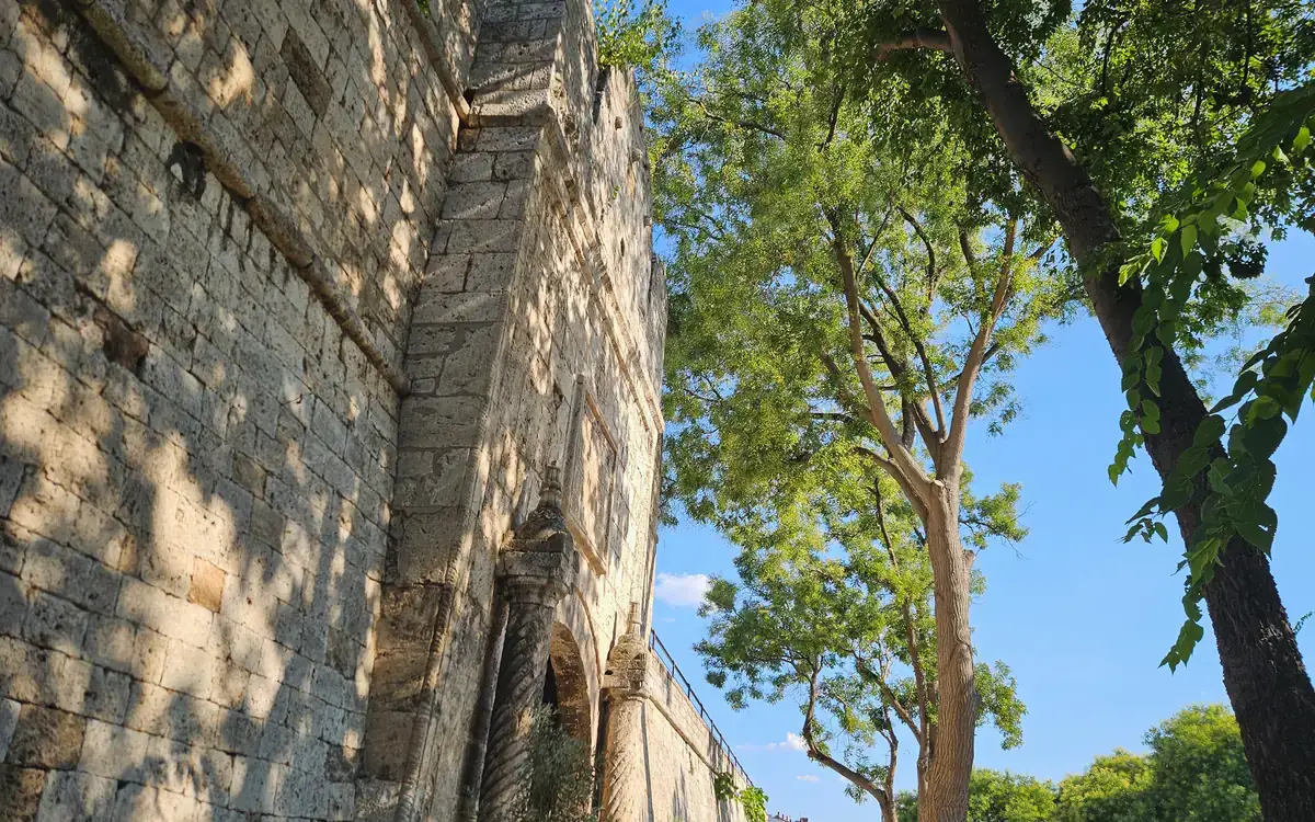 Old stone fortress walls beside a shaded walkway at Nis Fortress in Serbia.