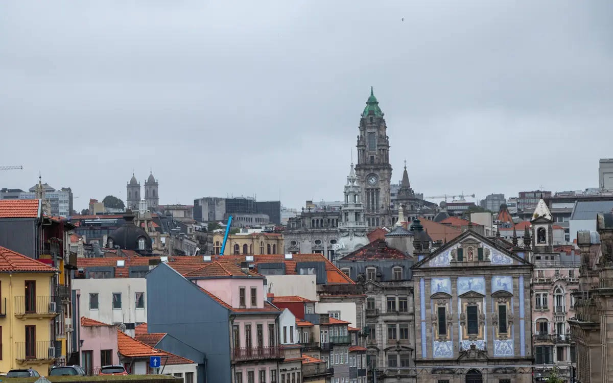 Historic center of Porto with rooftops and a tall tower under cloudy sky.