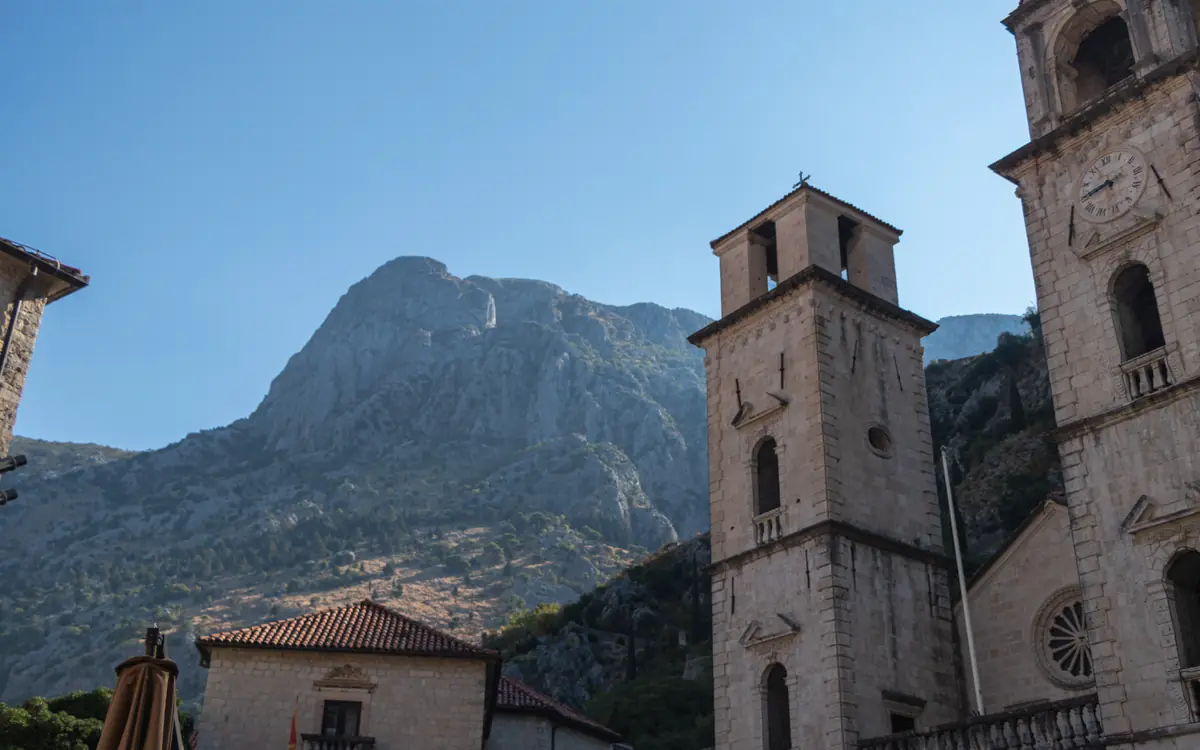 Cathedral towers below steep mountains in Kotor Old Town.