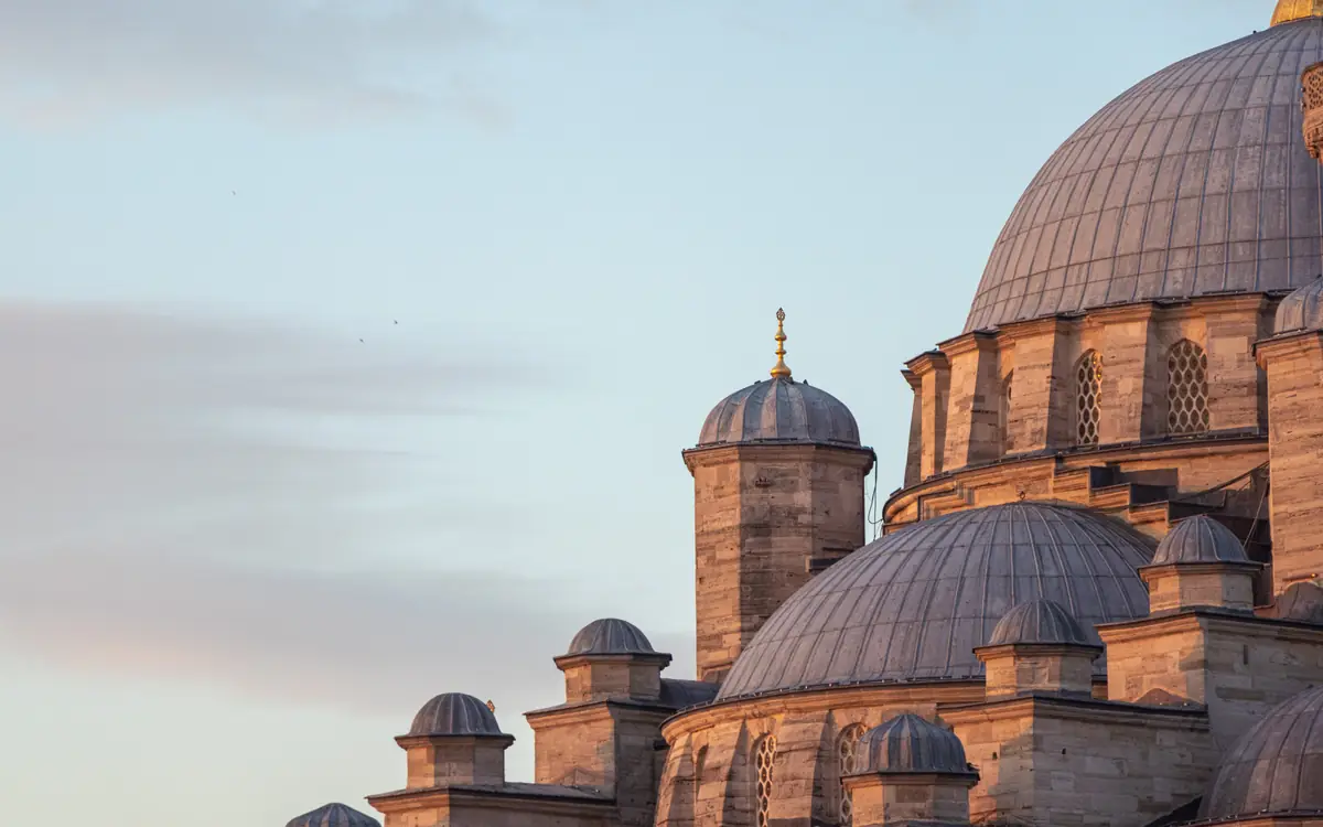 Close view of mosque domes and a small turret in warm light in Istanbul.