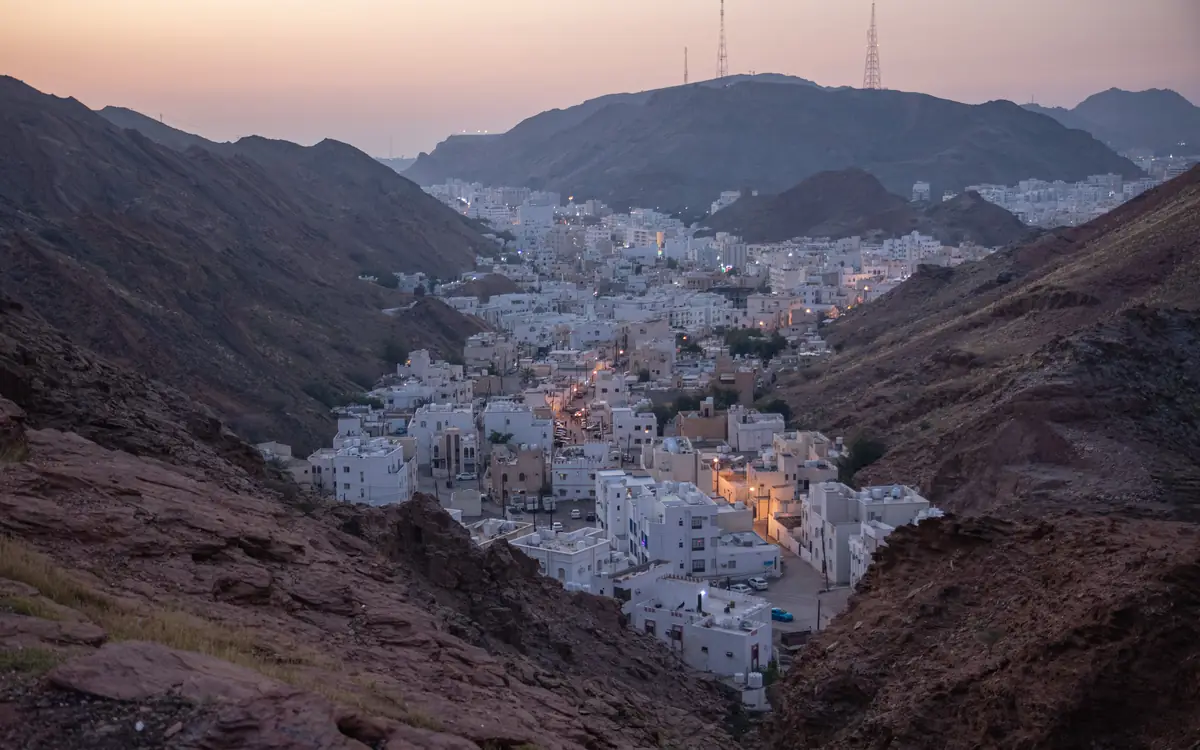 White city district with streetlights in a rocky mountain valley in Muscat.