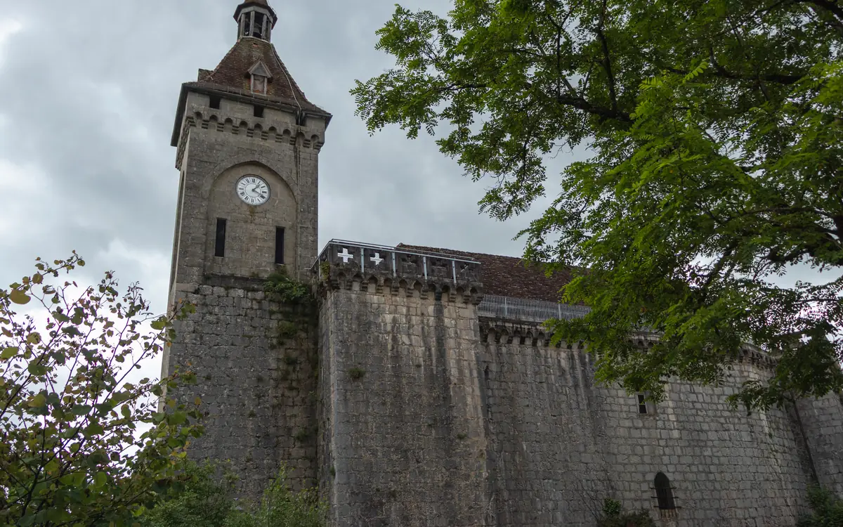 Stone clock tower, old masonry walls, and trees in a historic Montenegro old town.