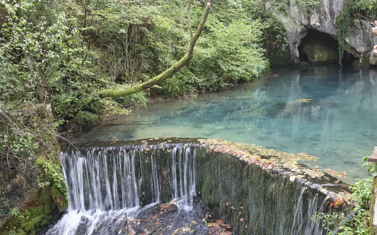 Clear turquoise water flowing over a low natural ledge at Krupajsko Vrelo in Serbia.