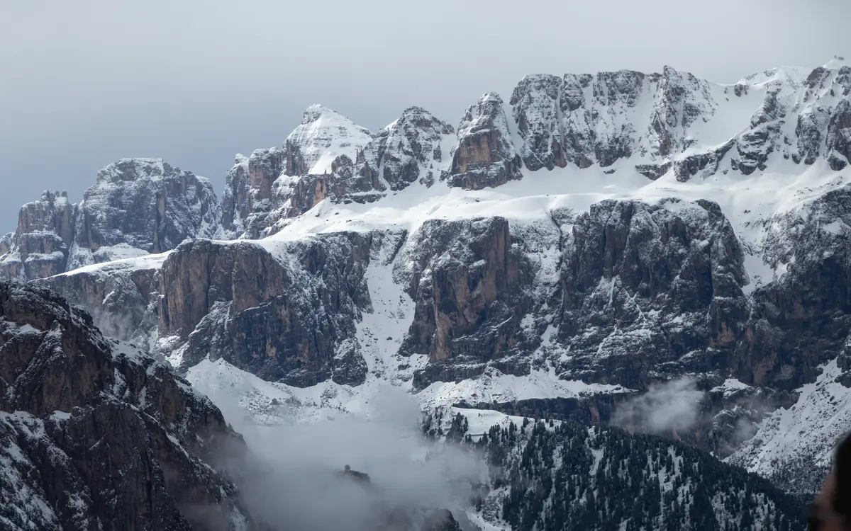 Jagged snow-covered peaks and cloud-wrapped lower slopes in the Italian Alps.