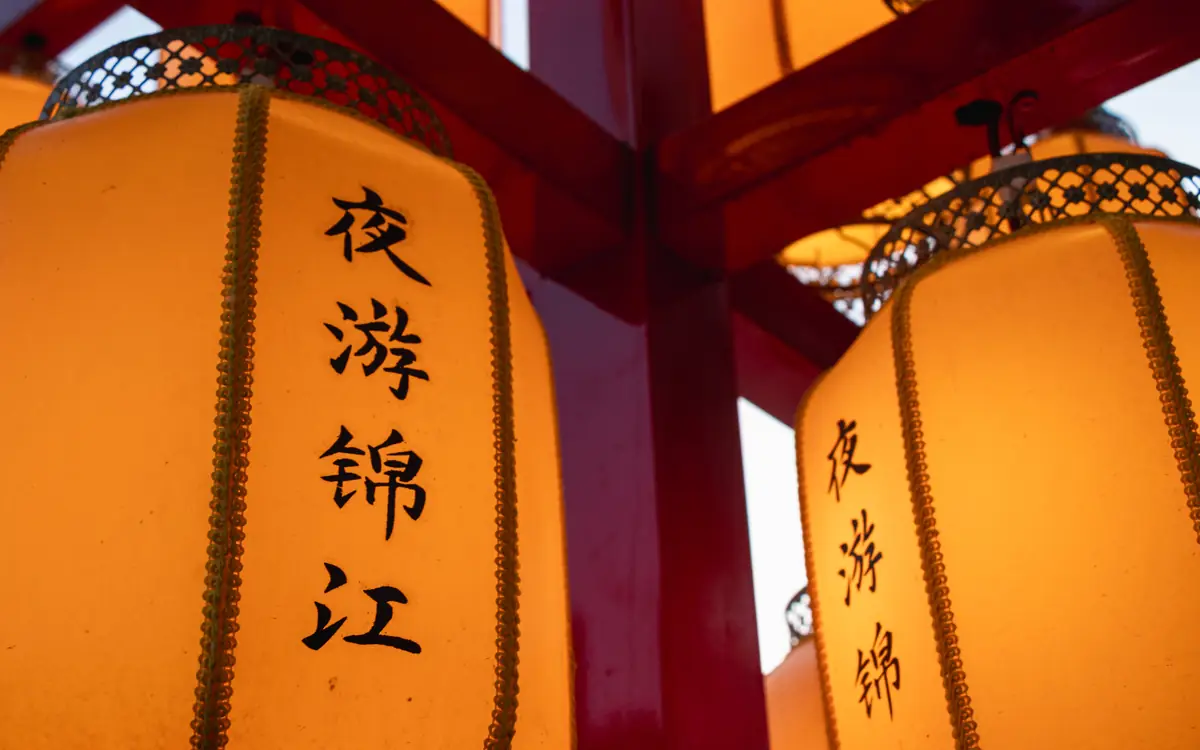 Close view of warm orange lanterns with Chinese characters on a night street in Chengdu.