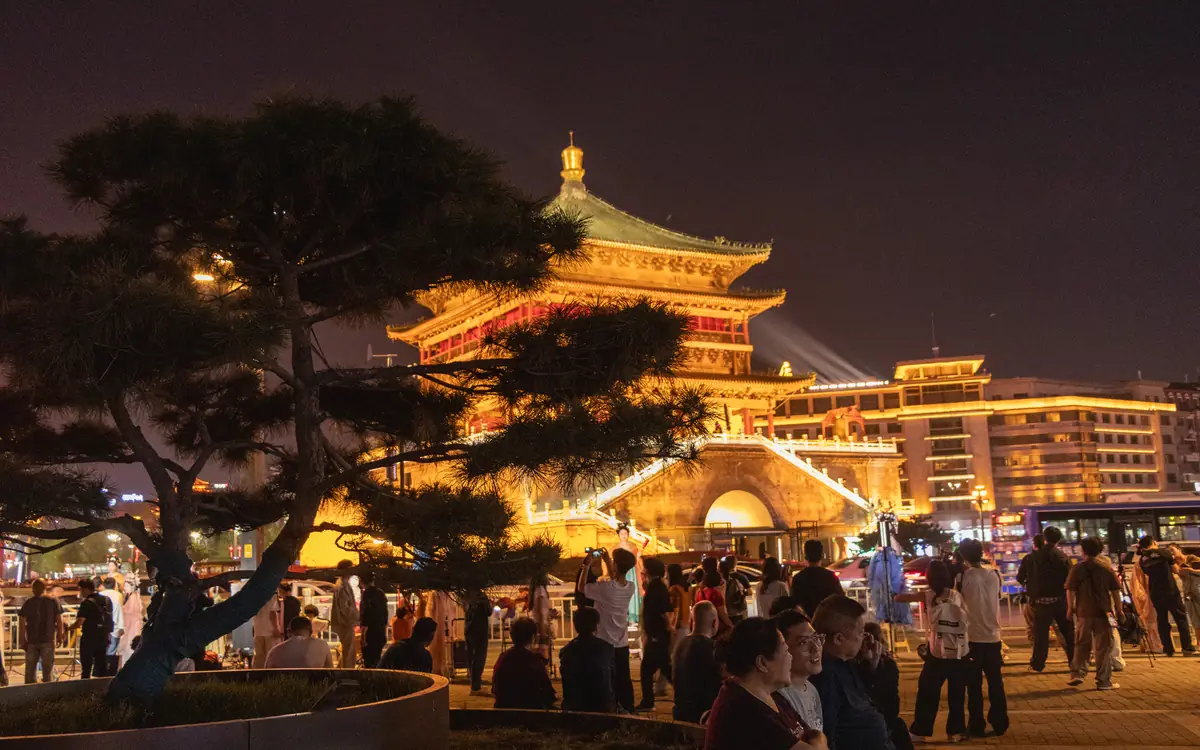 A lit historic tower above an evening crowd in Xi'an, China.