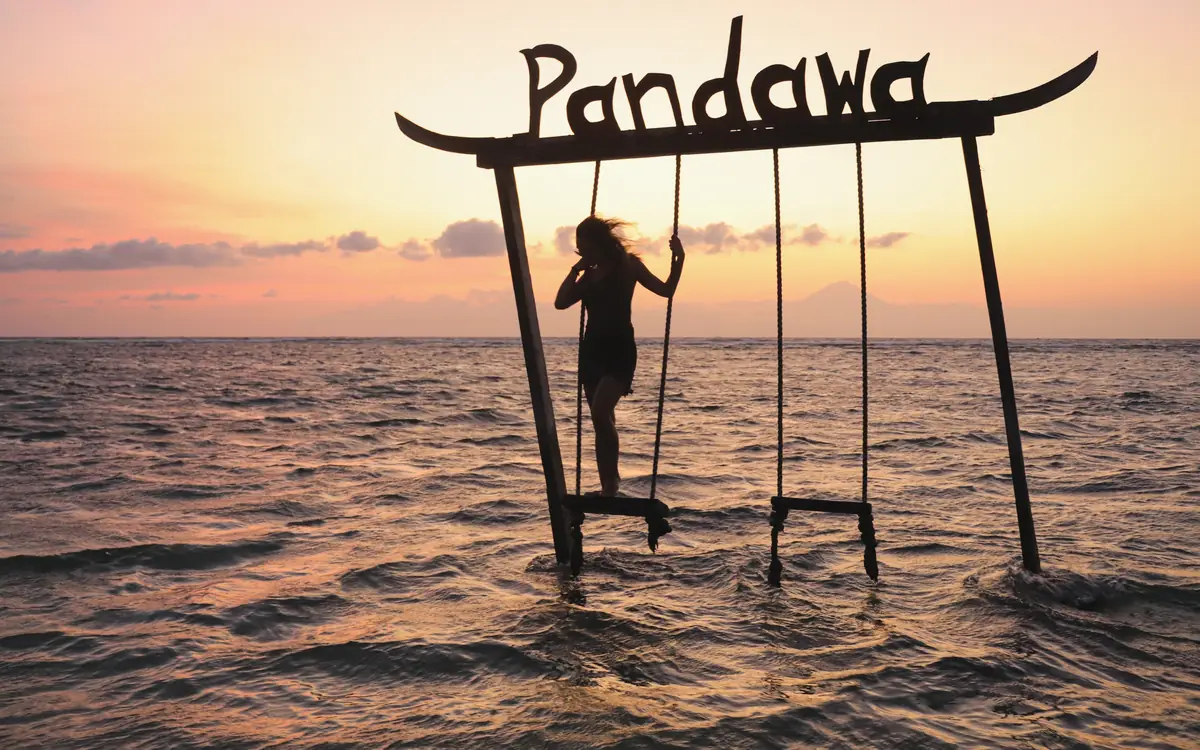 A swing set in shallow water near a beach in the Gili Islands.
